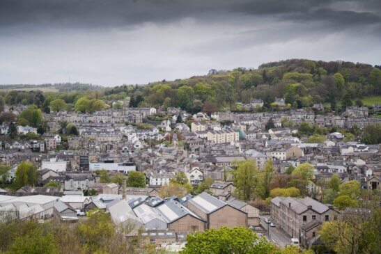 An aerial view over Kendal showing housing and factories with trees over in the distance.